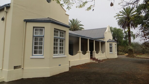 A building with a curved facade, large windows, and a covered porch area.