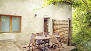 A patio with a wooden table and chairs, a window with blinds, and a wooden fence. - Self-contained accommodation in the heart of an acacia forest (Blésignac)