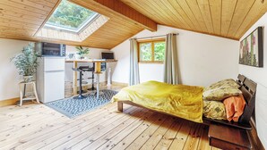 A cozy loft bedroom with a skylight, a bed, a desk, and a kitchenette. - Self-contained accommodation in the heart of an acacia forest (Blésignac)
