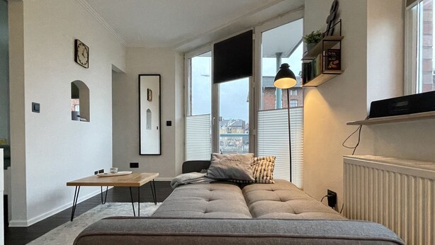 Un salon moderne avec un canapé, une petite table et une lampe.