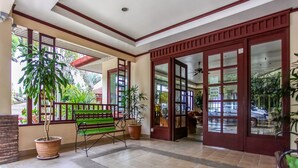Un espacio interior amplio con un banco, plantas en macetas y vistas al exterior.