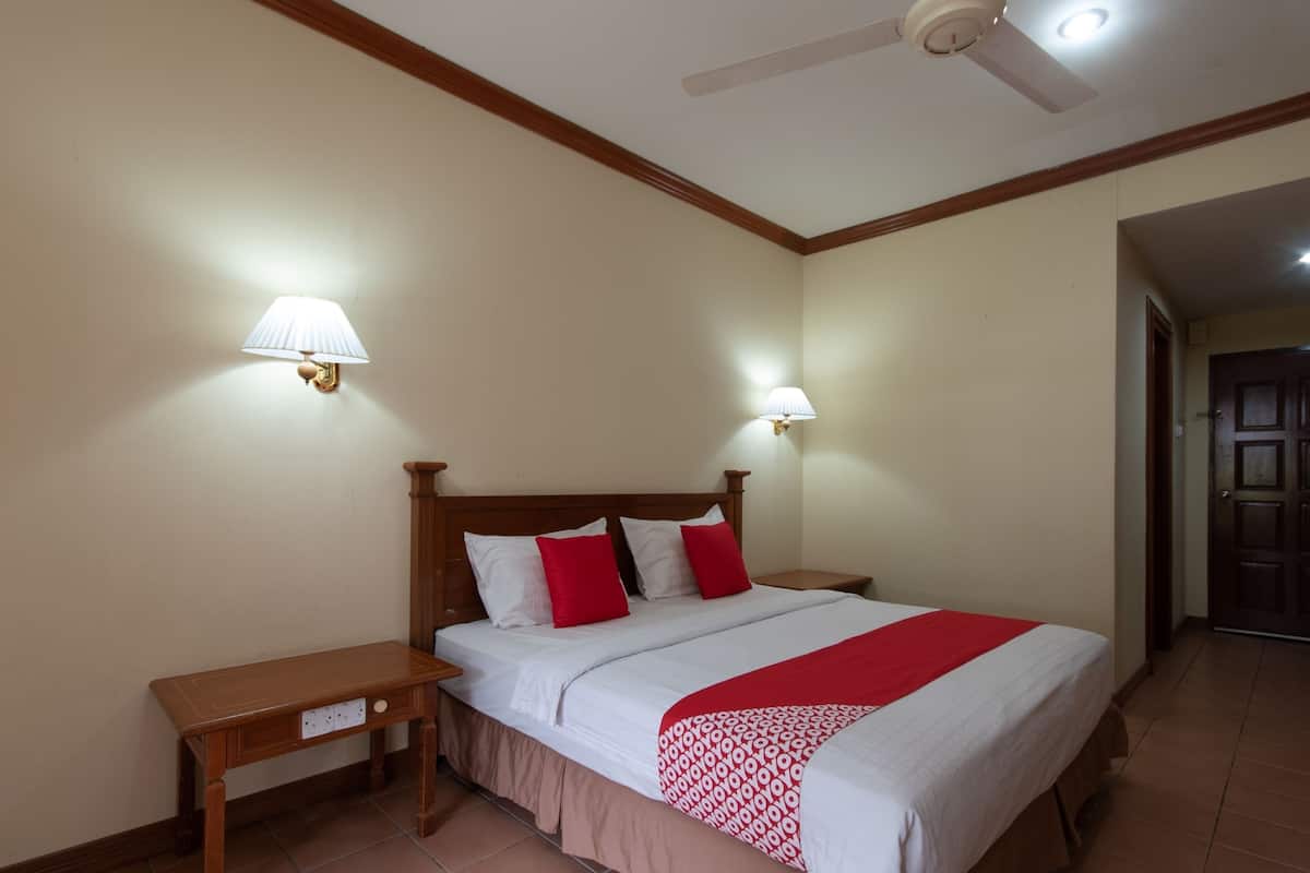 A hotel room with a wooden bed, two bedside tables, a ceiling fan, and two wall-mounted lamps.