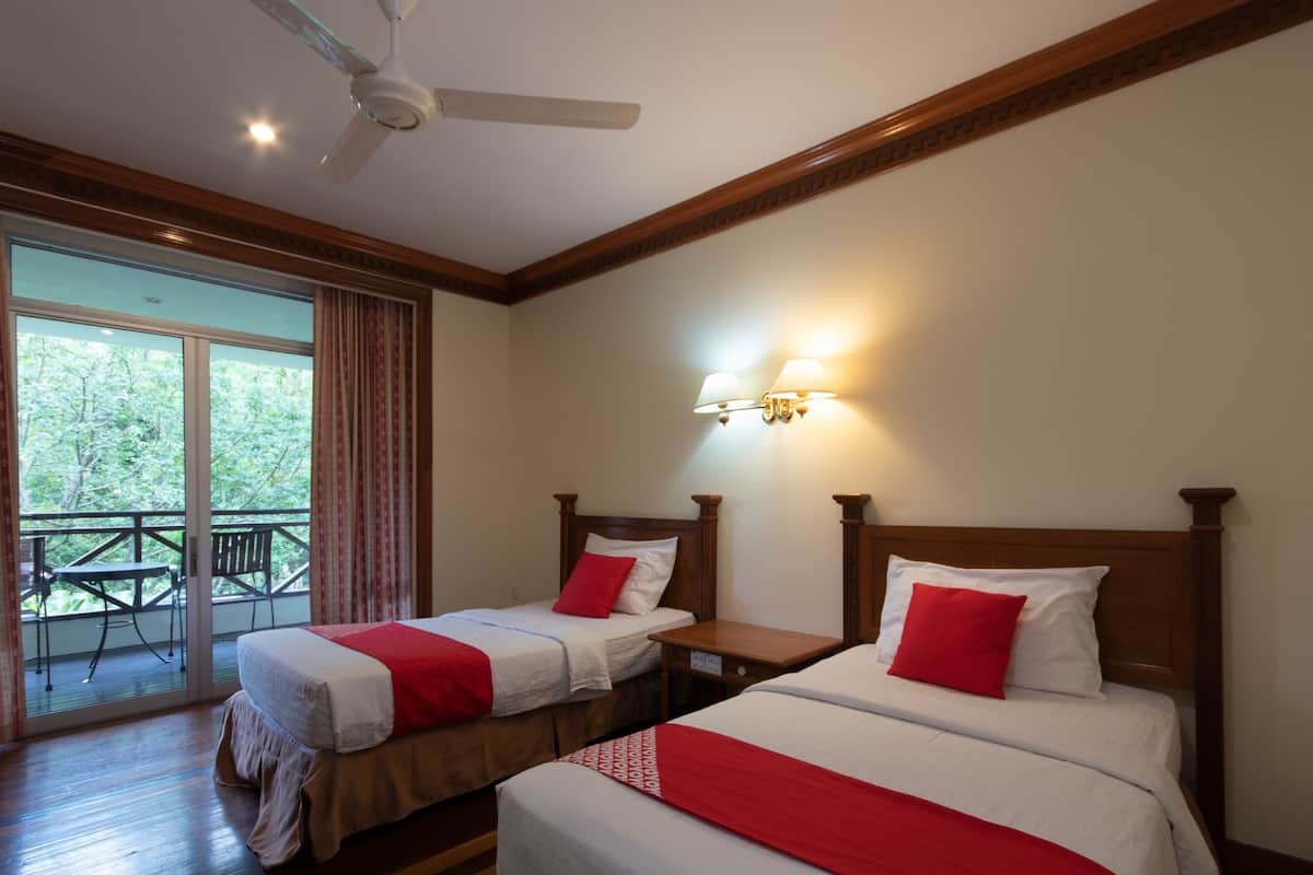 A hotel room with two beds, a balcony, and a ceiling fan.