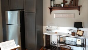 A kitchen with dark cabinets, a stainless steel refrigerator, a wooden shelf with 'Eat' and 'The South' signs, a glass display case, and a 'Wi-Fi' sign. -  Completely renovated single family home with new furnishings. (Mooresville)