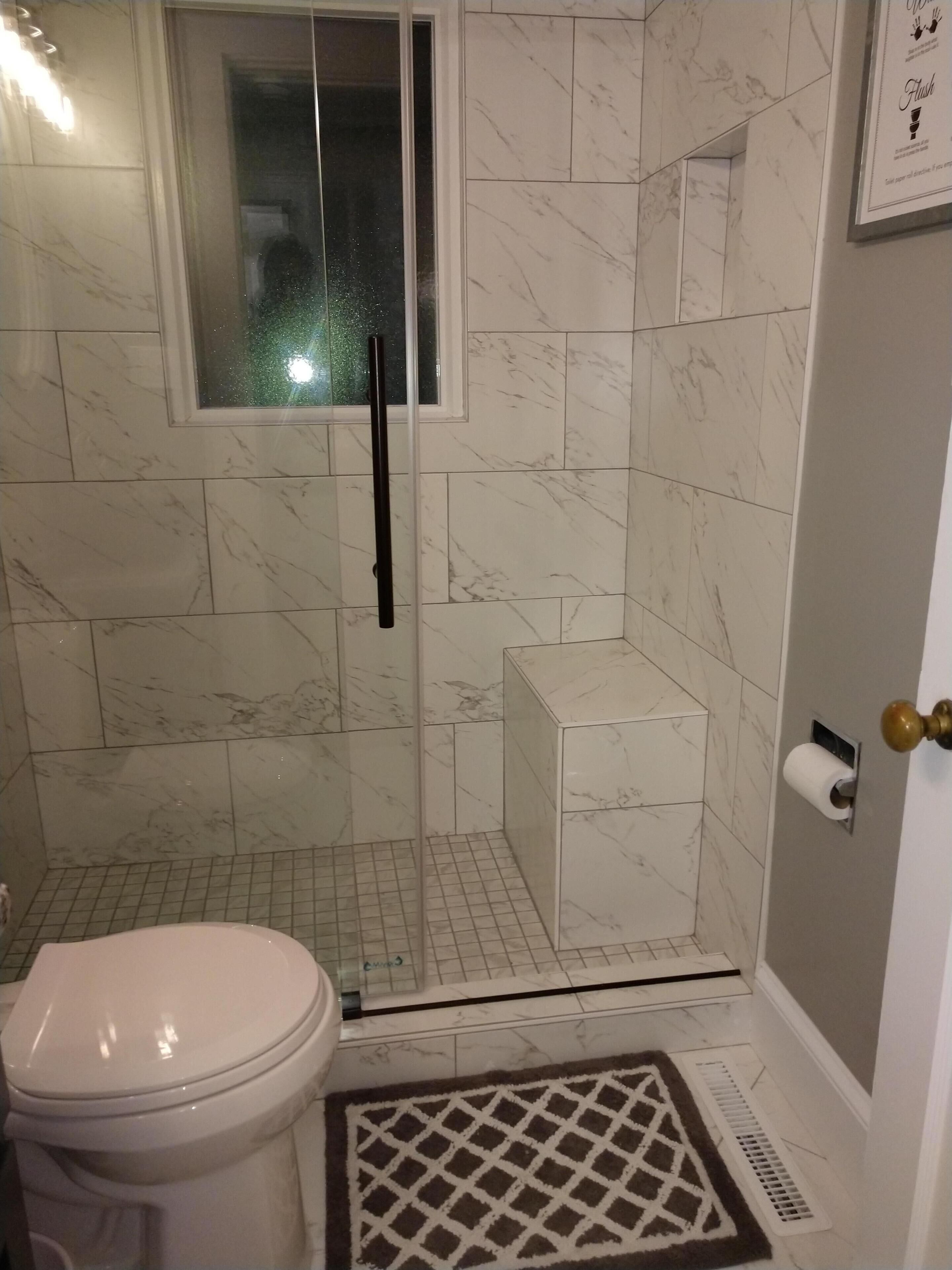 Un baño con inodoro, ducha con puerta de vidrio y un mueble blanco pequeño.