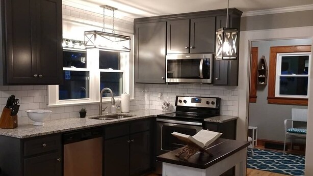 A modern kitchen with dark cabinets, stainless steel appliances, and a wooden floor. -  Completely renovated single family home with new furnishings. (Mooresville)