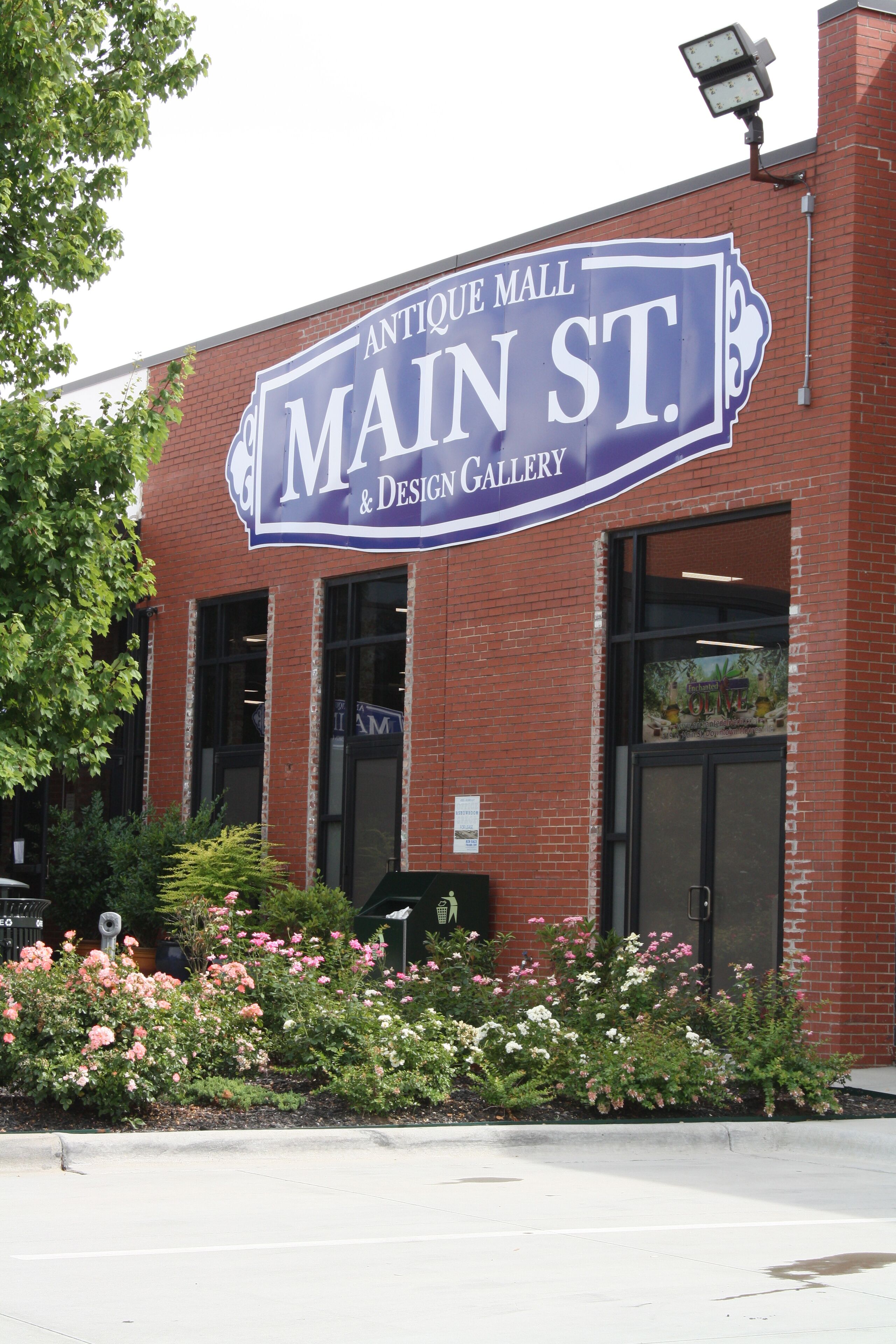 Un edificio de ladrillo con un gran letrero que dice 'Antique Mall Main St. & Design Gallery'.