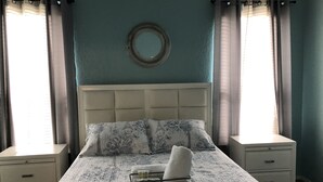 Un dormitorio con una cama, dos mesitas de noche y un espejo montado en la pared.