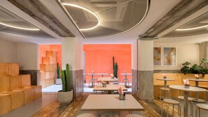 A modern interior with a central seating area, tables, and potted plants. - MoMo's Kuala Lumpur (Kuala Lumpur)