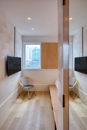 A modern hotel room with a large window, two chairs, a bench, and a flat-screen TV on the wall. - MoMo's Kuala Lumpur (Kuala Lumpur)