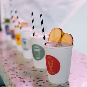 A row of beverage cups with straws, each topped with a slice of fruit, on a speckled surface. - MoMo's Kuala Lumpur (Kuala Lumpur)