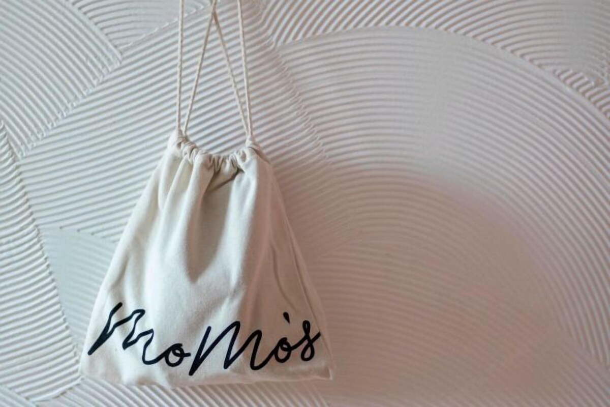 A white drawstring bag with the word 'Momo's' written on it.
