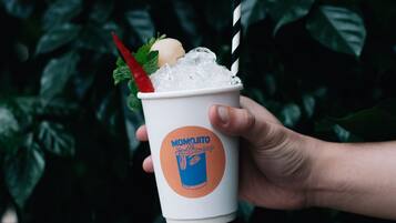 A hand holding a cup with a drink and a straw, labeled "MOMOJITO".