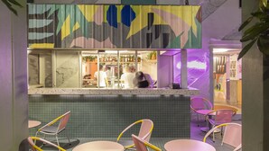 An indoor seating area with tables and chairs, a tiled floor, hanging plants, and a colorful wall mural. - MoMo's Kuala Lumpur (Kuala Lumpur)