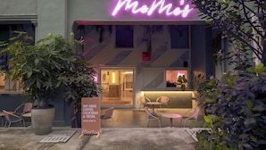 A cafe with a neon sign, outdoor seating, and potted plants. - MoMo's Kuala Lumpur (Kuala Lumpur)