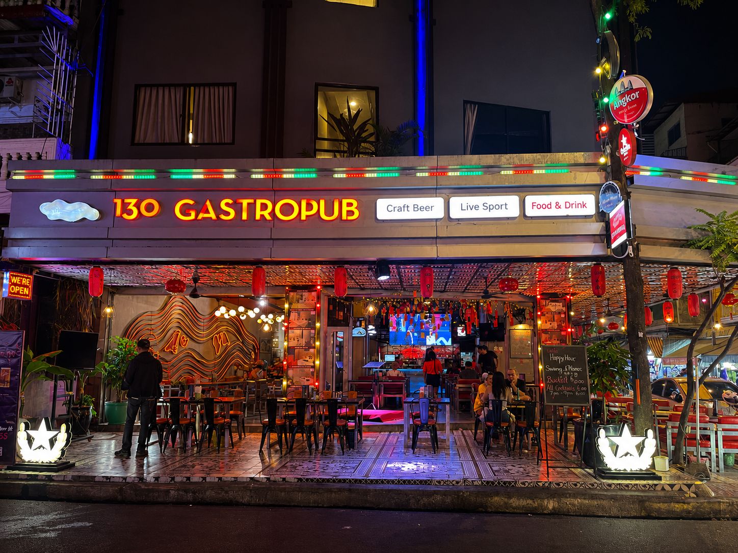 Un gastropub con terraza, letreros de neón y diversas comodidades, incluyendo cerveza artesanal, deportes en vivo y opciones de comida y bebida.