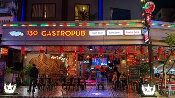 Un gastropub con terraza, letreros de neón y diversas comodidades, incluyendo cerveza artesanal, deportes en vivo y opciones de comida y bebida.