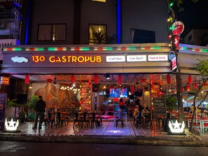 A gastropub with outdoor seating, neon signage, and a variety of amenities including craft beer, live sports, and food & drink options.