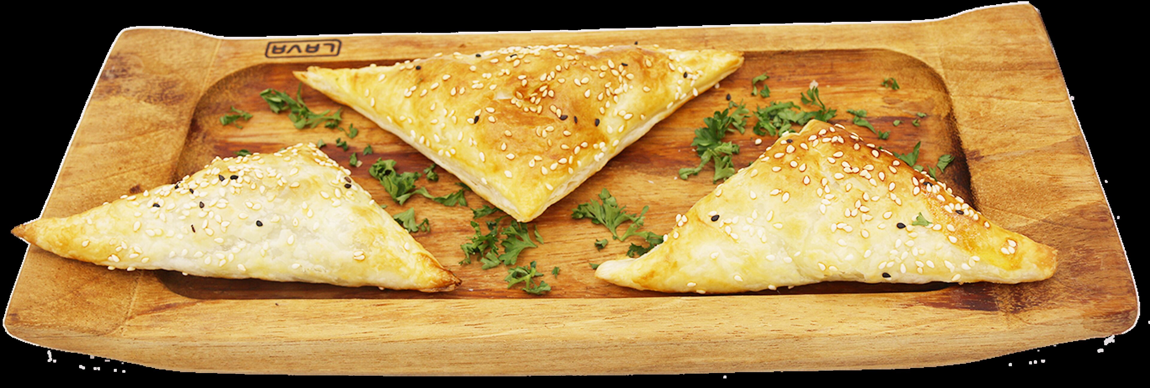 Three triangular pastries on a wooden board with sesame seeds.