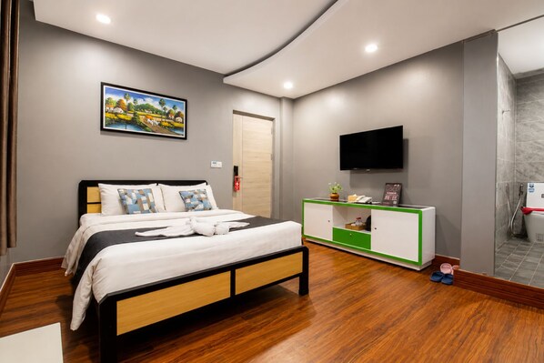 A hotel room with a bed, a TV, a cabinet, and a shower area. - Ostro Hotel (Phnom Penh)