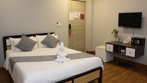 A hotel room with a bed, a desk, a TV, and a door with a fire safety sign. - Ostro Hotel (Phnom Penh)