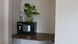 A small, enclosed storage space with a metal shelf, a glass vase with a plant, and a black radio. - Ostro Hotel (Phnom Penh)