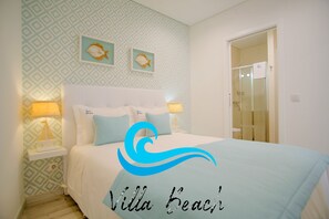 A bedroom with a bed, two bedside lamps, a nightstand, and a wall with a geometric pattern.