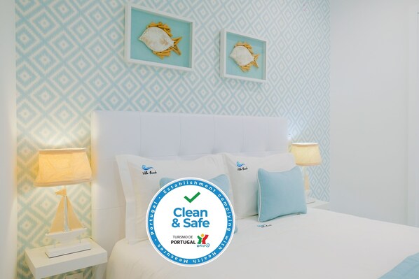 A hotel room with a bed, two nightstands, and a wall with framed pictures.