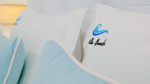 Primer plano de un almohadón blanco con un logotipo azul y la inscripción 'Hello Beach'.