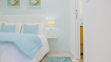 Une chambre à coucher avec un lit, une table de chevet, une lampe et un mur décoré d’un motif.