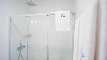 Un baño moderno con cabina de ducha de vidrio, una toalla colgada en la pared y un cabezal de ducha instalado en el techo.