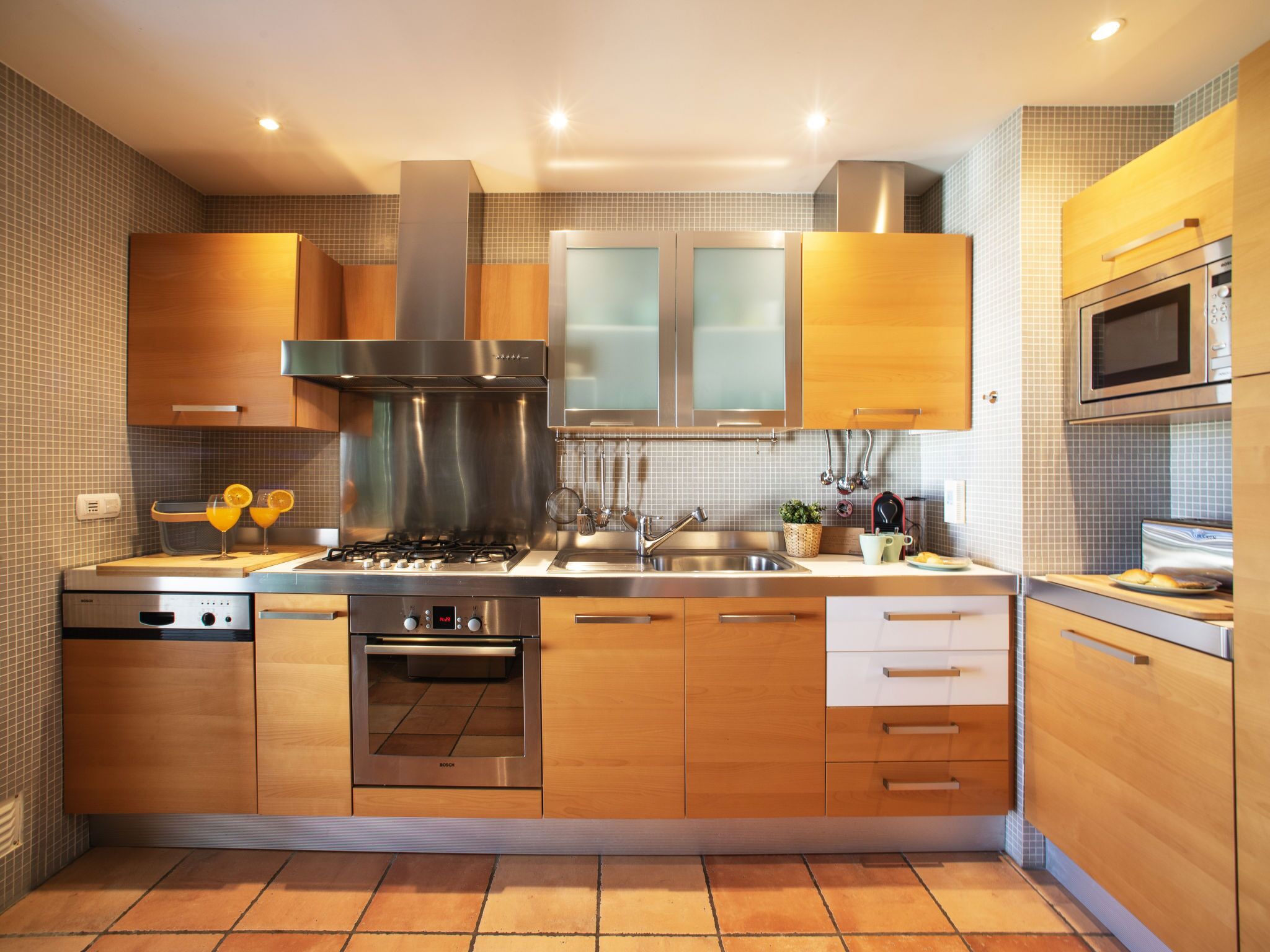 A modern kitchen with stainless steel appliances, wooden cabinets, and a tiled backsplash.