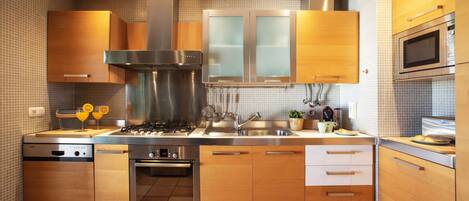 A modern kitchen with stainless steel appliances, wooden cabinets, and a tiled backsplash.