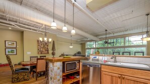 A kitchen with a wooden counter, stainless steel appliances, and a dining area with a chair and table. - Gallery at 35 Patton (Asheville)
