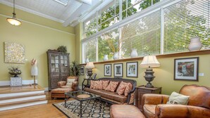 A spacious living room with a large window, a fireplace, and a variety of seating options including a sofa, armchairs, and a coffee table. - Gallery at 35 Patton (Asheville)