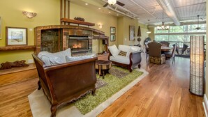 A spacious living room with a fireplace, comfortable seating, and a ceiling fan. - Gallery at 35 Patton (Asheville)
