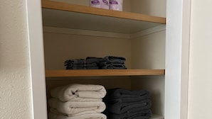 Un placard avec trois étagères, chacune contenant des serviettes pliées de couleurs différentes.