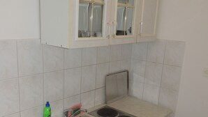 A compact kitchen with a sink, stove, and cabinets. - Apartments Travarevic (Dubrovnik)