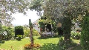 A garden with a pergola, a dining table, and chairs. - Apartments Travarevic (Dubrovnik)