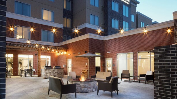 A hotel courtyard with outdoor seating, a fire pit, and string lights. - Residence Inn Richmond Midtown/Glenside (Richmond)
