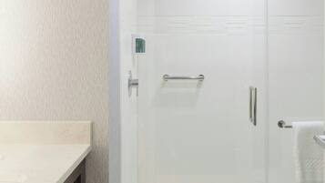 A modern bathroom with a glass-enclosed shower, a vanity with a towel rack, and a toilet.
