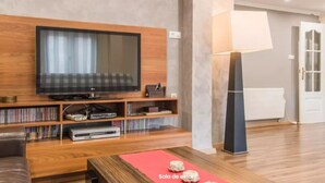 A modern living room with a flat-screen TV, wooden shelves, a red mat, and a floor lamp. - Quiet and bright apartment. WIFI + FREE BREAKFAST (València)