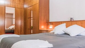 A bedroom with a bed, a wooden wardrobe, a bedside table with a lamp, and a mirror. - Quiet and bright apartment. WIFI + FREE BREAKFAST (València)