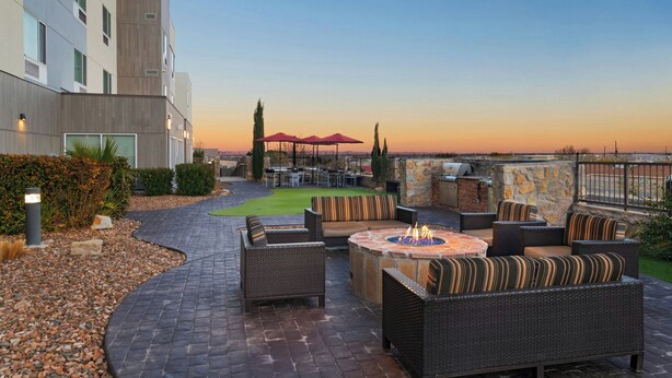 An outdoor patio with wicker furniture, a fire pit, and a stone wall. - TownePlace Suites by Marriott El Paso North (El Paso)