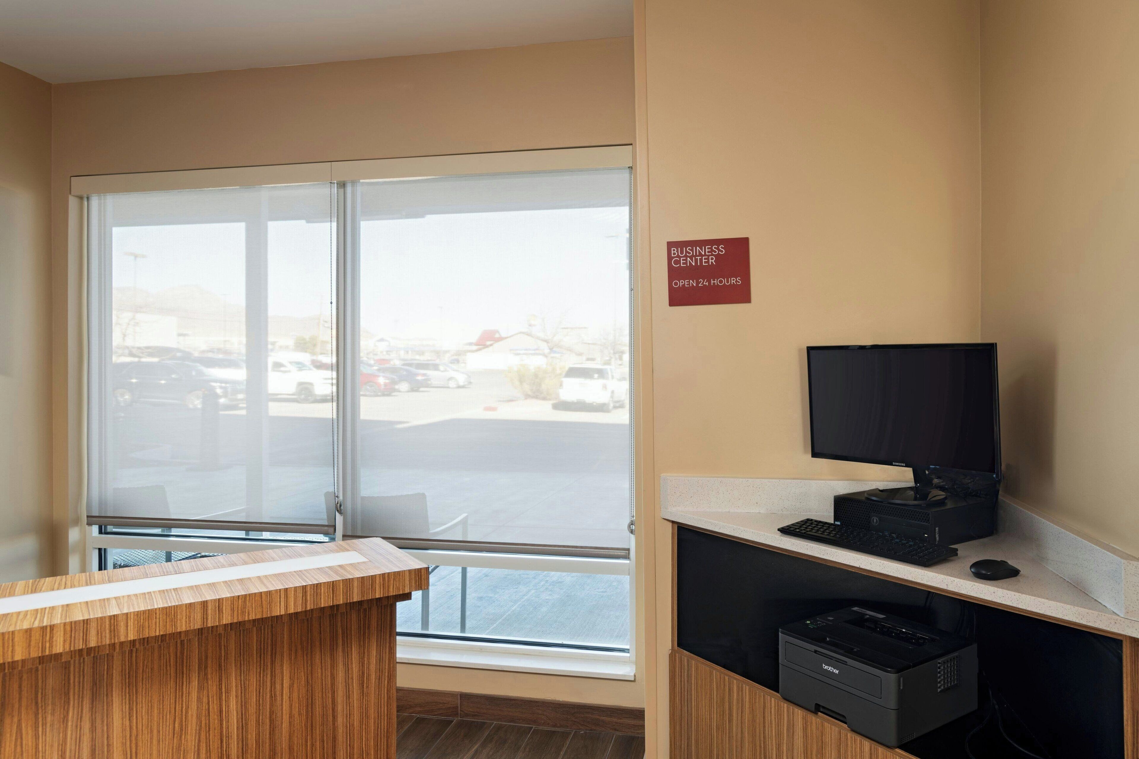 A business center with a reception desk, a computer, and a printer.