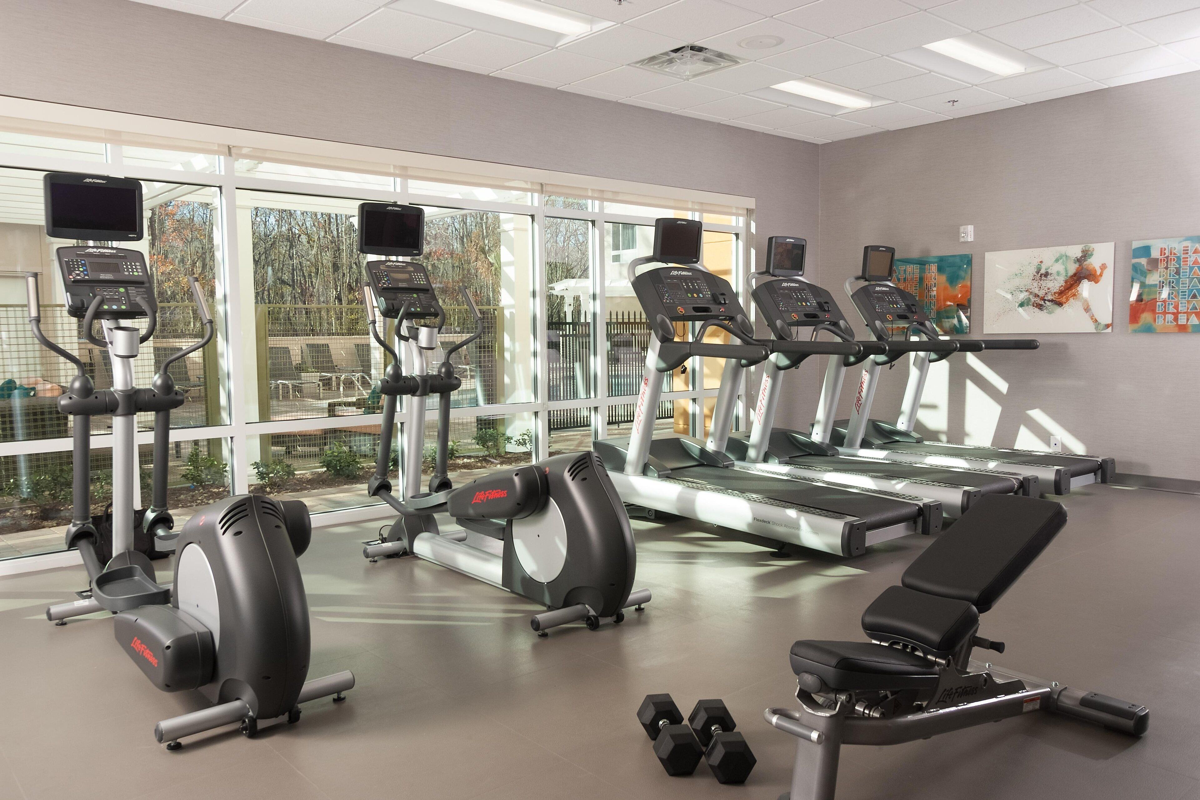Un gimnasio con cintas de correr, elípticas y pesas.