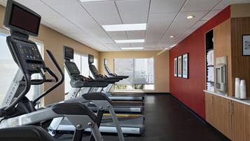 A gym with treadmills, exercise equipment, and large windows offering views of the city.
