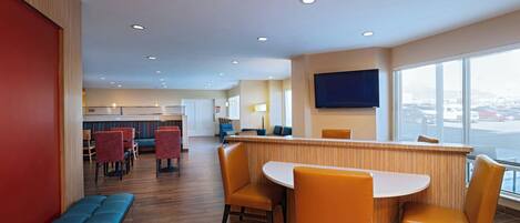 A modern hotel lobby with a reception desk, seating area, and large windows offering a view.