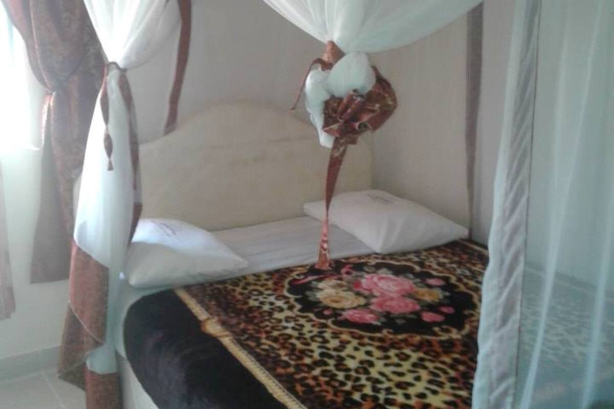 A bed with a canopy, a patterned bedspread, and a pillow.