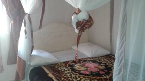 Ein Bett mit Baldachin, einer Bettdecke mit Leopardenmuster und weißen Kissen.